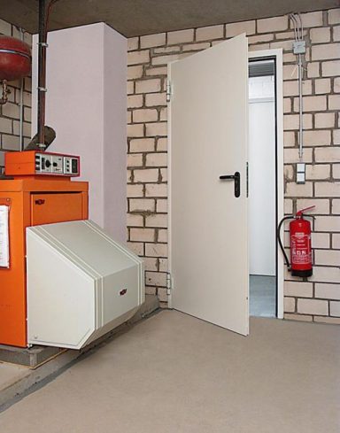 Chaudière orange à côté d'une porte ouverte menant à une pièce. Extincteur visible.