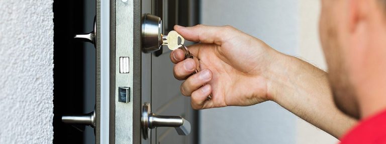 Une main insérant une clé dans une serrure de porte.