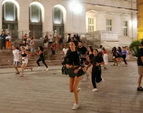 Un groupe de jeunes court dans une rue animée la nuit.