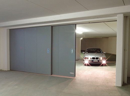 Porte de garage ouverte avec une voiture à l'intérieur d'un stationnement.