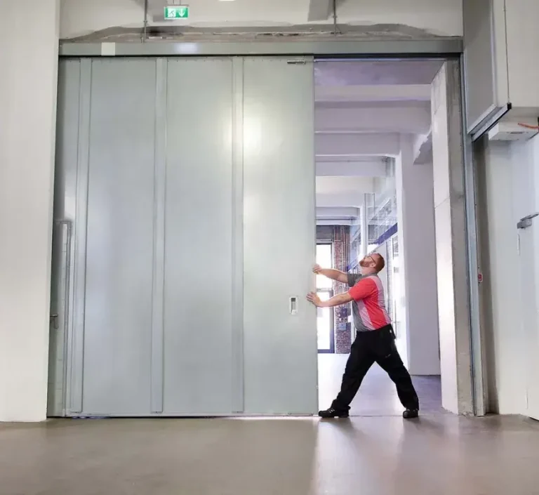 Personne en train d’ouvrir une grande porte coulissante dans un espace intérieur moderne.